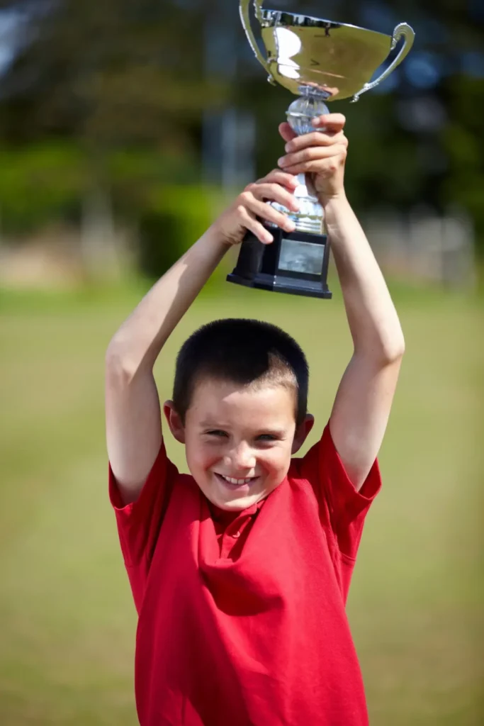 boy cheering with trophy outdoors 2023 11 27 05 28 03 utc scaled 1